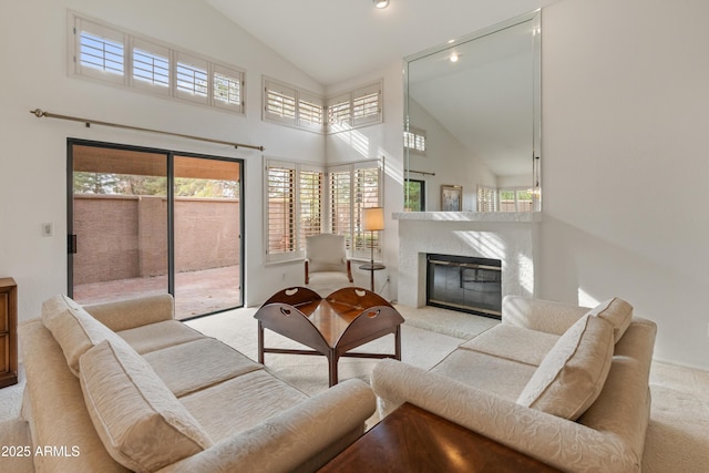 carpeted living room with high vaulted ceiling and a premium fireplace