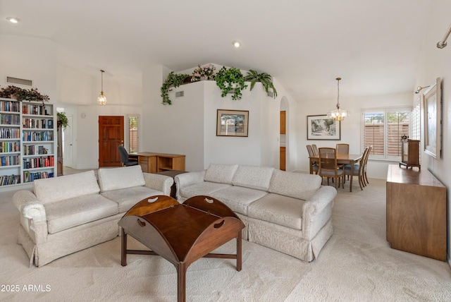 living room featuring light carpet, a notable chandelier, and vaulted ceiling