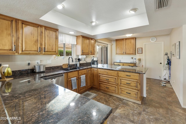 kitchen featuring dishwasher, a raised ceiling, sink, dark stone countertops, and kitchen peninsula