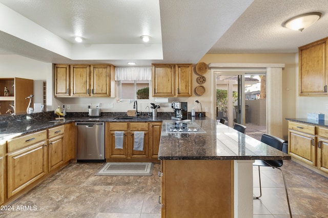 kitchen with kitchen peninsula, a kitchen breakfast bar, stainless steel dishwasher, a textured ceiling, and sink