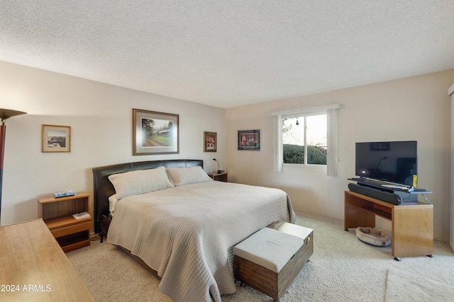 bedroom with light colored carpet and a textured ceiling