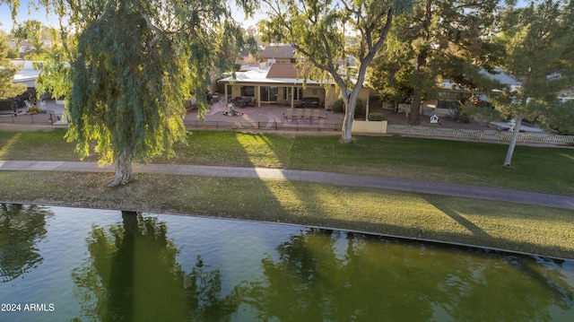 back of house featuring a water view, a patio area, and a lawn