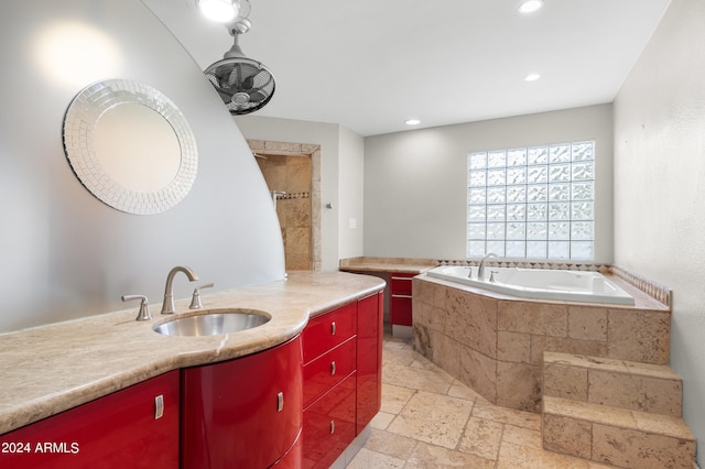 bathroom featuring a relaxing tiled tub, vanity, and tile patterned floors