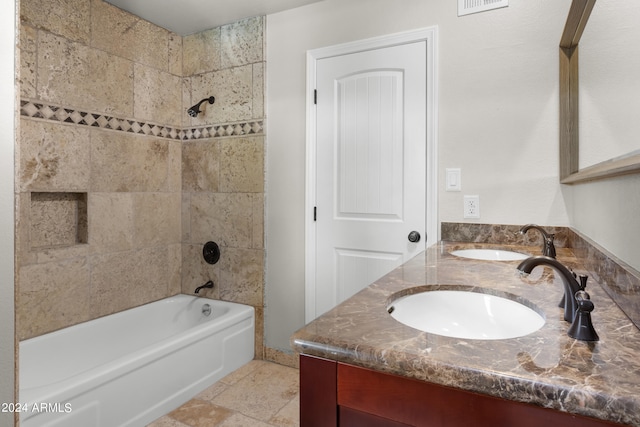 bathroom with dual vanity, tiled shower / bath combo, and tile patterned floors