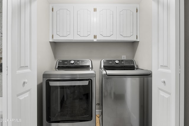 laundry room featuring separate washer and dryer and cabinets