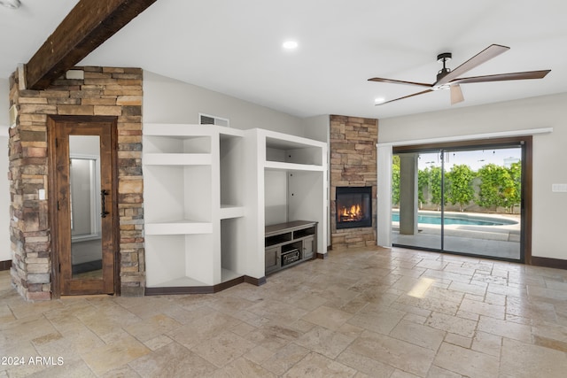 unfurnished living room featuring a stone fireplace, light tile patterned floors, built in shelves, beam ceiling, and ceiling fan