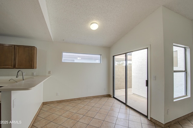 interior space featuring lofted ceiling, sink, light tile patterned floors, and a textured ceiling