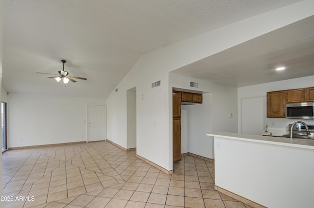 kitchen featuring light tile patterned floors, ceiling fan, stove, a textured ceiling, and vaulted ceiling