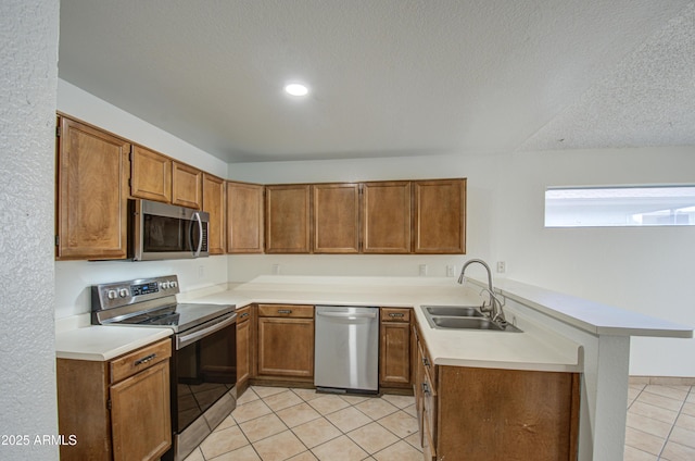 kitchen with sink, appliances with stainless steel finishes, a textured ceiling, light tile patterned flooring, and kitchen peninsula