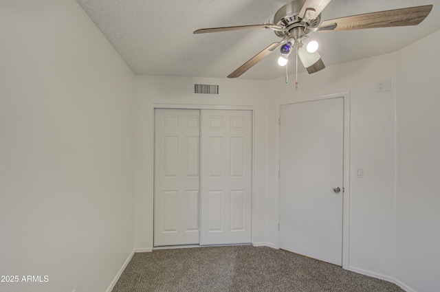 unfurnished bedroom with ceiling fan, carpet floors, a textured ceiling, and a closet