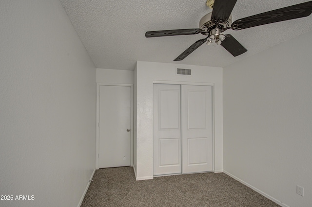 unfurnished bedroom with ceiling fan, carpet floors, a closet, and a textured ceiling