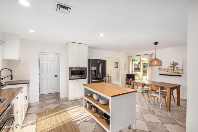 kitchen with visible vents, open shelves, a sink, butcher block countertops, and stainless steel appliances