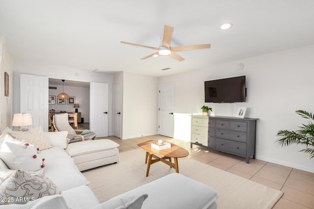 living area with light tile patterned floors, visible vents, baseboards, and ceiling fan