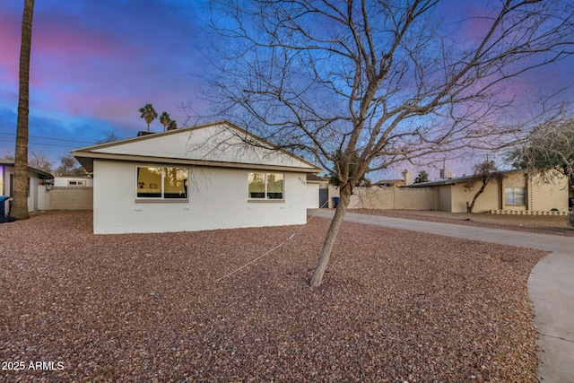 property exterior at dusk with fence and driveway