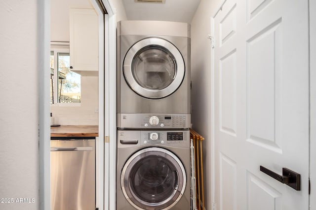 washroom featuring stacked washer and clothes dryer and laundry area