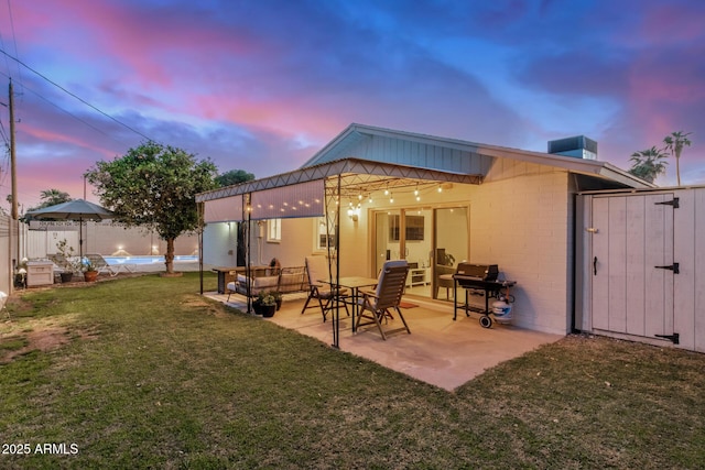 rear view of property with a gate, a patio, fence, a yard, and a fenced in pool