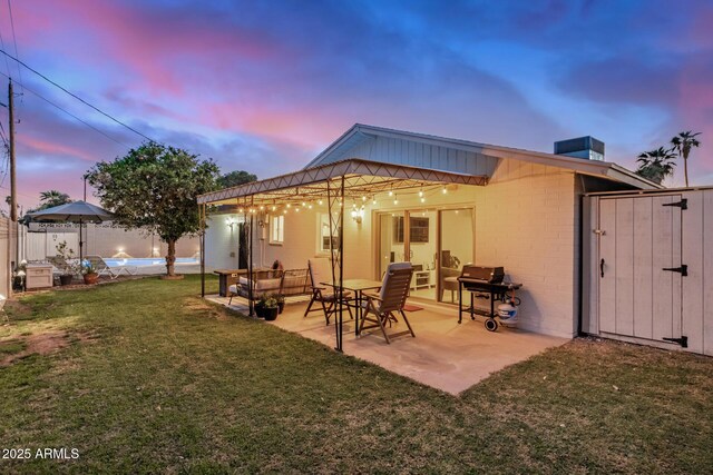 back of house with brick siding, a fenced in pool, fence, a yard, and a patio