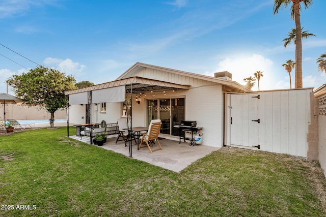 rear view of property with a gate, a fenced in pool, fence, a patio area, and a lawn