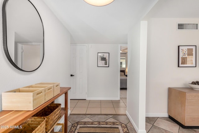 interior space featuring vaulted ceiling, light tile patterned flooring, baseboards, and visible vents