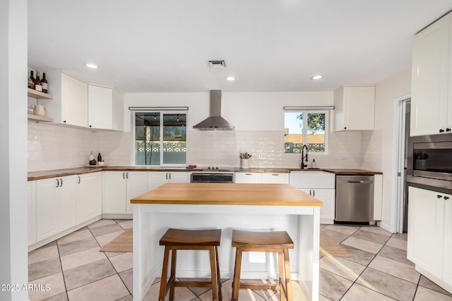 kitchen featuring visible vents, butcher block counters, stainless steel appliances, and wall chimney exhaust hood