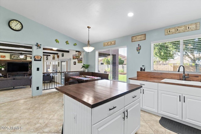 kitchen with wooden counters, decorative light fixtures, sink, and white cabinets