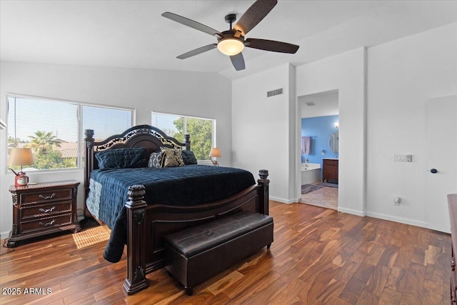 bedroom featuring multiple windows, hardwood / wood-style floors, connected bathroom, and vaulted ceiling