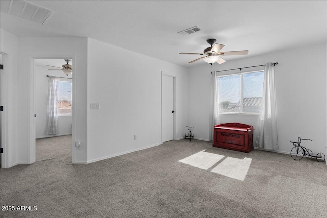 empty room with a wealth of natural light, light carpet, and ceiling fan