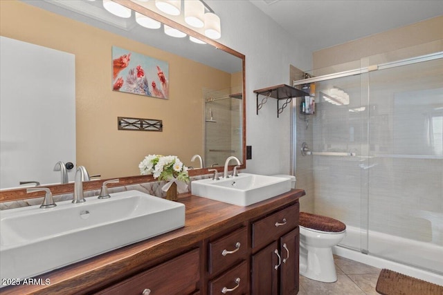 bathroom with a shower with door, vanity, tile patterned floors, and toilet