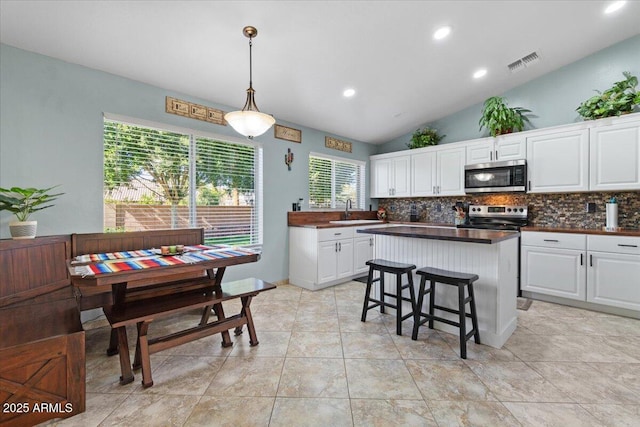 kitchen featuring tasteful backsplash, white cabinetry, appliances with stainless steel finishes, and pendant lighting