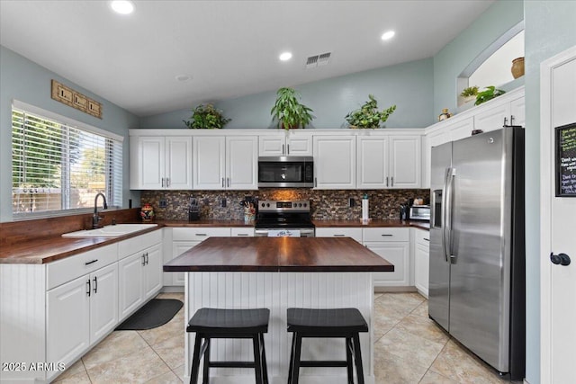 kitchen featuring wood counters, tasteful backsplash, sink, white cabinets, and stainless steel appliances