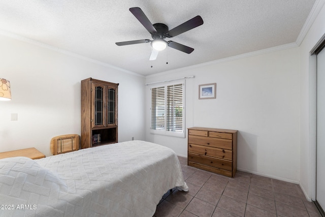 bedroom with ceiling fan, tile patterned floors, ornamental molding, and a textured ceiling