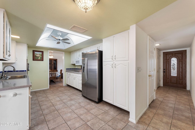 kitchen with sink, light tile patterned floors, ceiling fan, white cabinetry, and stainless steel refrigerator with ice dispenser