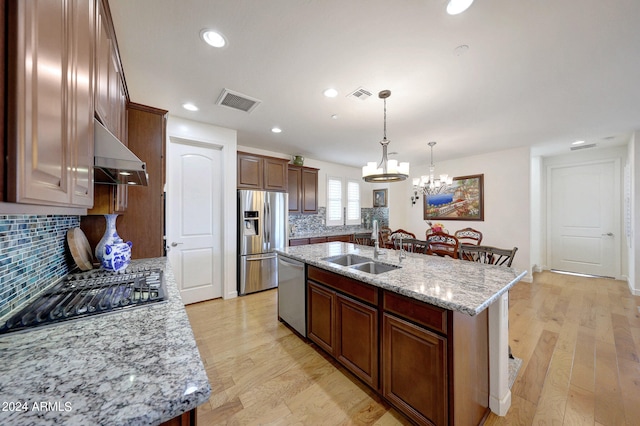 kitchen featuring appliances with stainless steel finishes, light hardwood / wood-style floors, and an island with sink