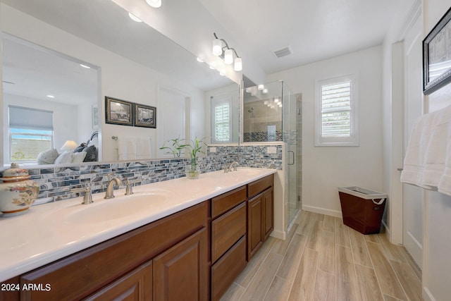 bathroom featuring a wealth of natural light, backsplash, a shower with shower door, and vanity