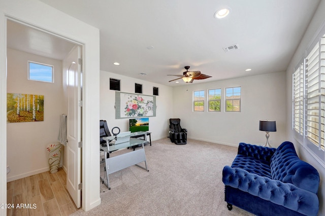 living area featuring light hardwood / wood-style flooring, ceiling fan, and plenty of natural light