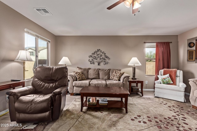 living room featuring ceiling fan, light wood-type flooring, and a wealth of natural light