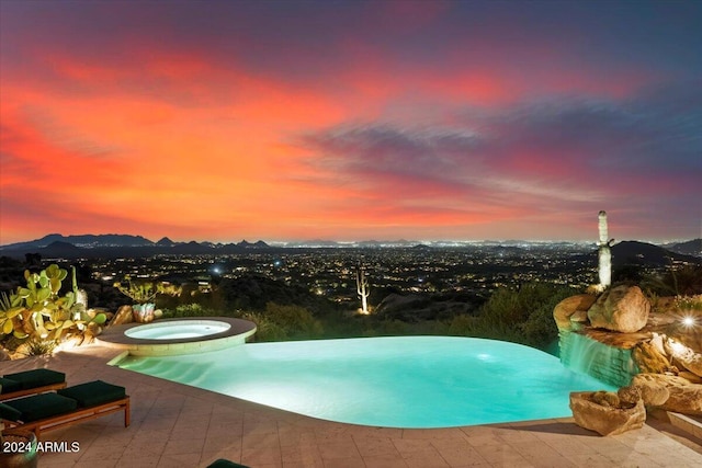 pool at dusk with an in ground hot tub