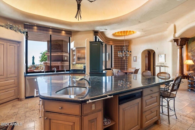 kitchen featuring a large island with sink, an inviting chandelier, a kitchen bar, dark stone countertops, and sink