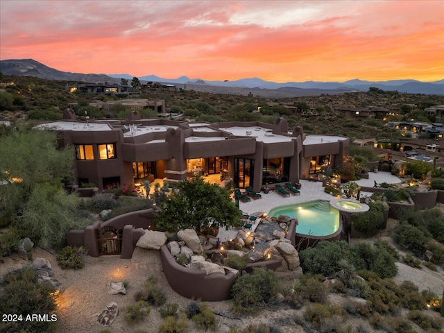 back house at dusk featuring a patio and a mountain view