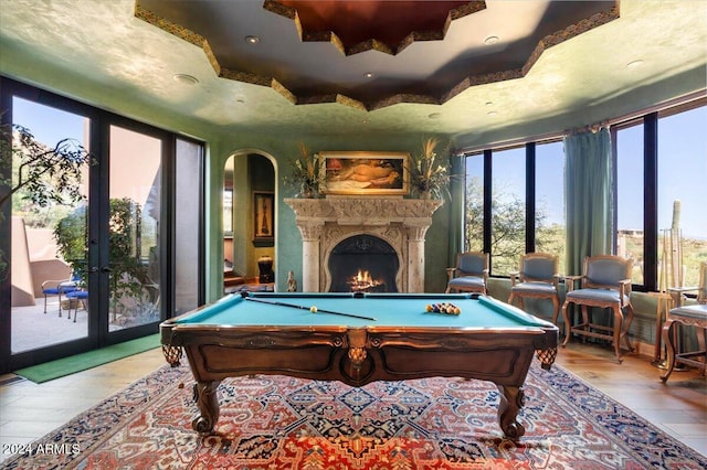 playroom featuring pool table, light hardwood / wood-style flooring, and a tray ceiling