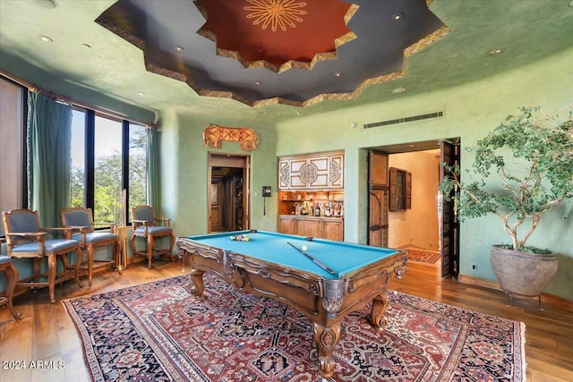 recreation room with hardwood / wood-style flooring, billiards, and a raised ceiling