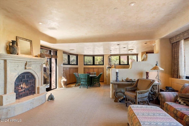 living room featuring a high end fireplace, carpet, and a textured ceiling