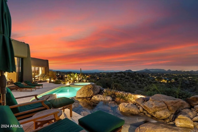 pool at dusk featuring a patio