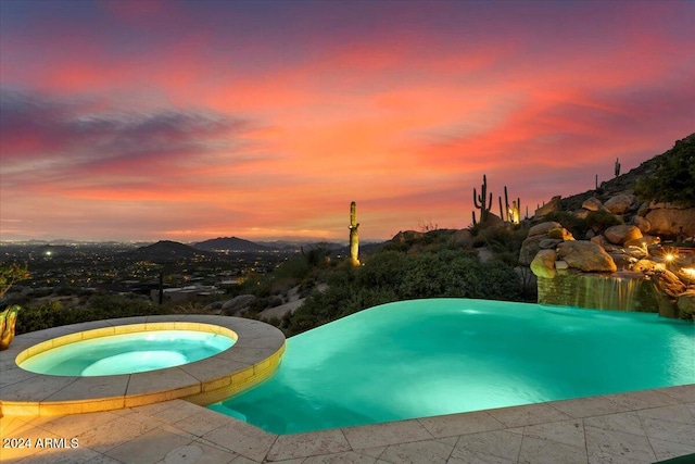 pool at dusk featuring an in ground hot tub