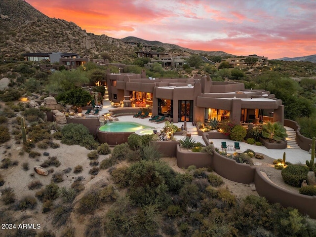 back house at dusk featuring a jacuzzi and a mountain view