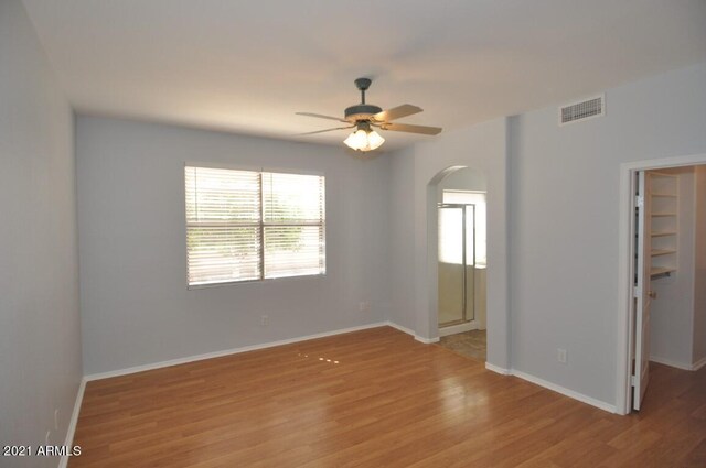 18071 W Douglas Way, Surprise, AZ 85374 - empty room featuring arched walkways, ceiling fan, light wood-style flooring, and baseboards