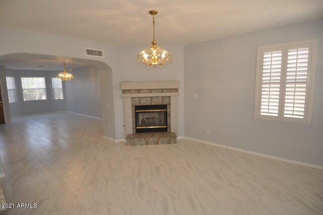 18071 W Douglas Way, Surprise, AZ 85374 - unfurnished living room featuring a chandelier, arched walkways, a tiled fireplace, and baseboards