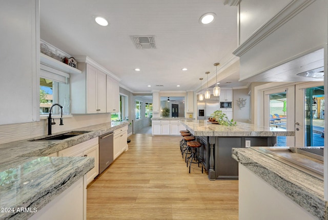 kitchen featuring a center island, pendant lighting, sink, white cabinetry, and appliances with stainless steel finishes