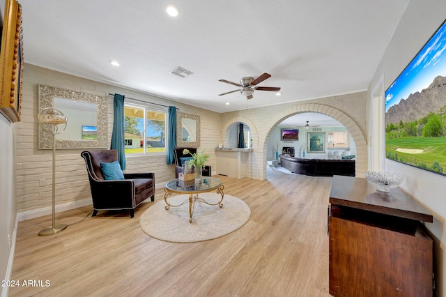 living room featuring brick wall, ceiling fan, and light hardwood / wood-style flooring