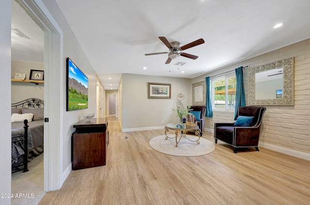 living area with brick wall, ceiling fan, and light hardwood / wood-style flooring